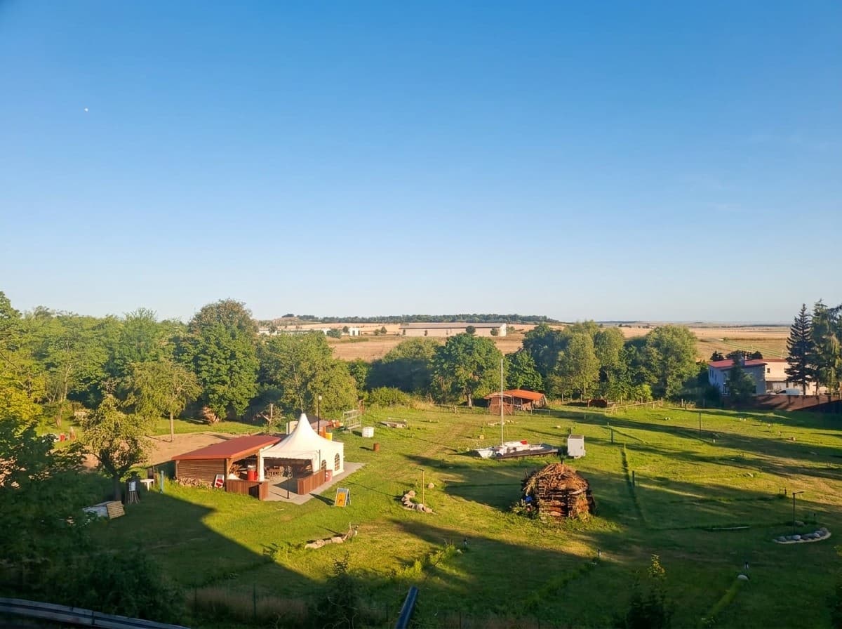 Der Campingplatz am Morgen unter klarem blauem Himmel, links der Pavillon